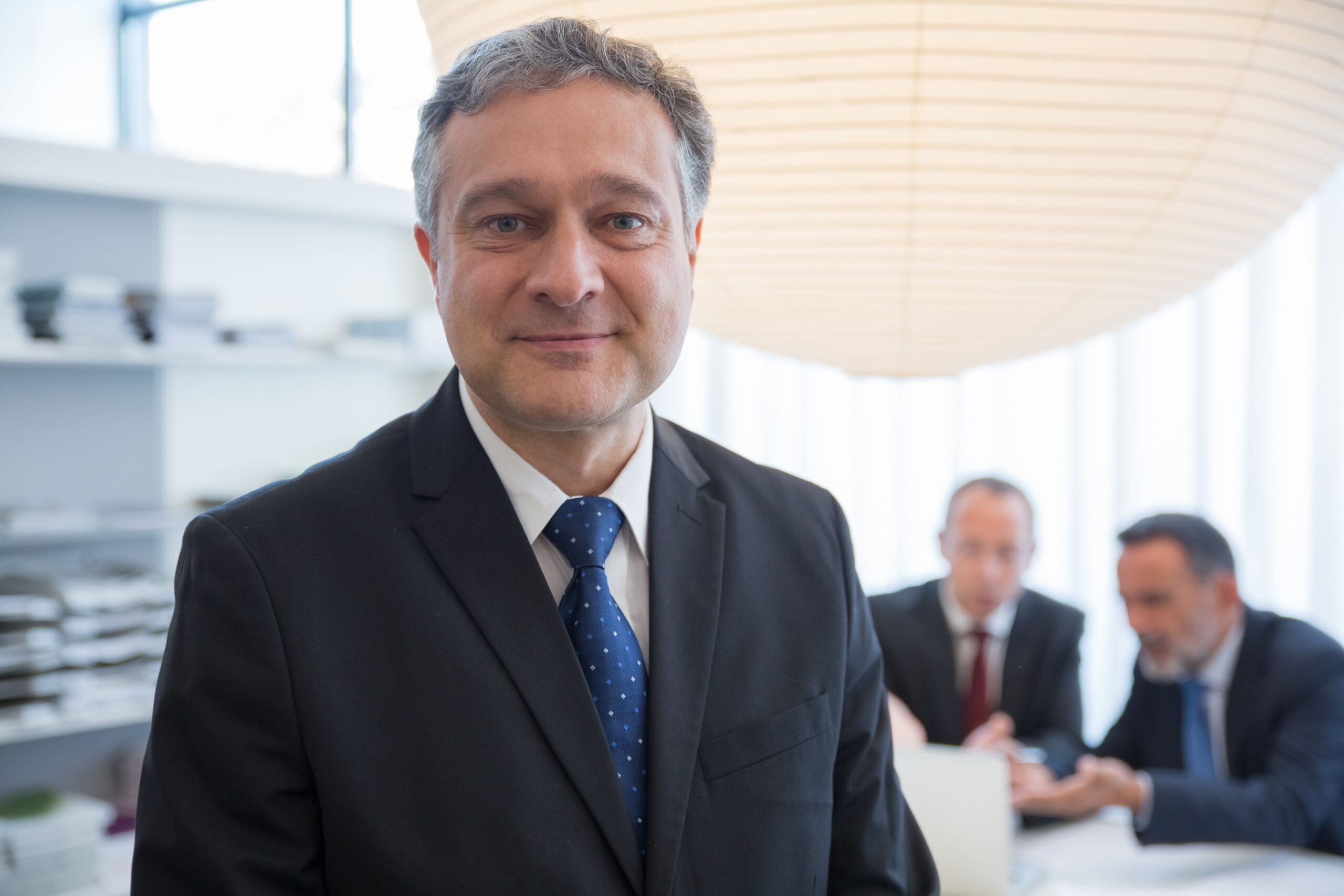 Home Businessman in a suit with colleagues in a modern office in Portugal.
